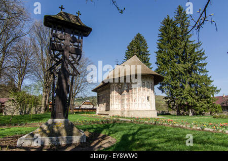 Die gemalten Klöster Rumäniens Historisches Kloster mit lebhaften Fresken, eingebettet in eine grüne Landschaft unter einem hellblauen Himmel Stockfoto