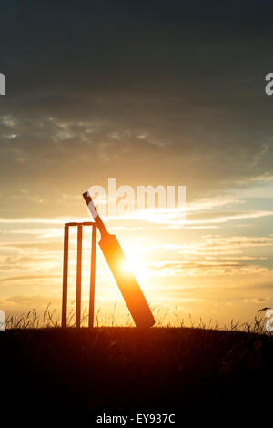 Kricketschläger und Stümpfe bei Sonnenuntergang. Silhouette Stockfoto