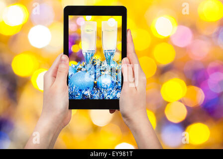 Mann nimmt Foto von Weihnachten Stillleben - zwei Gläser Champagner am blauen Xmas Lametta mit gelb und violett verwischt Weihnachten Stockfoto