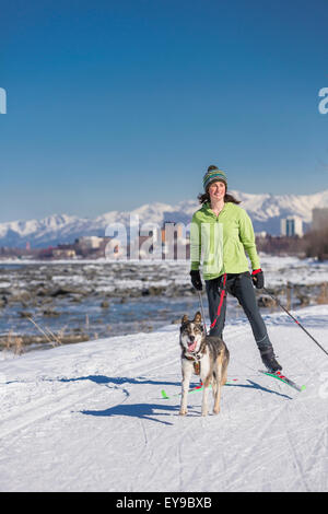 Eine junge Frau Skijors mit ihrem Alaska Husky Schlittenhunde unten Yunan Tony Knowles Coastal Trail, Anchorage, Alaska, USA. Stockfoto