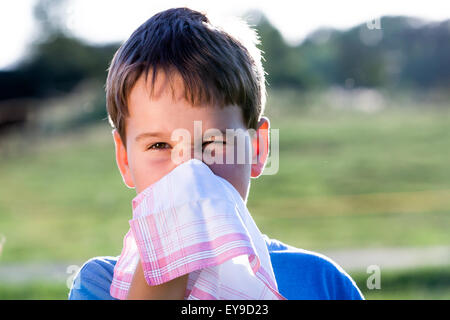 Kind mit einer Allergie gegen Pollen, während Sie Ihre Nase mit einem weißen Taschentuch, in der Natur schneuzen Stockfoto