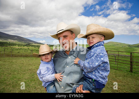 Landwirtschaft - stellt ein Montana Cowboy in einem Gehege halten Sie seine beiden kleinen Söhne / in der Nähe von Stanford, Montana, USA. Stockfoto