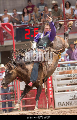 Cheyenne, Wyoming, USA. 24. Juli 2015. Bareback Reiter Tyler Skalen von Abfindungen, Colorado hängt an kleinen Dougy im Cheyenne Frontier Days Rodeo in Frontier Park Arena 24. Juli 2015 in Cheyenne, Wyoming. Frontier Days feiert die Cowboy Traditionen des Westens mit einem Rodeo, Parade und Fair. Stockfoto