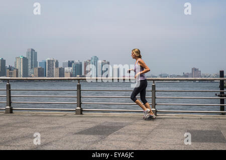 Frau, laufen, Joggen im Hudson River Park.  Manhattan, Jersey City im Hintergrund. NEW YORK CITY. USA. Stockfoto