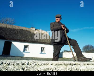 Co Galway, Irland; Bauer steht vor seinem Reetdachhaus Stockfoto