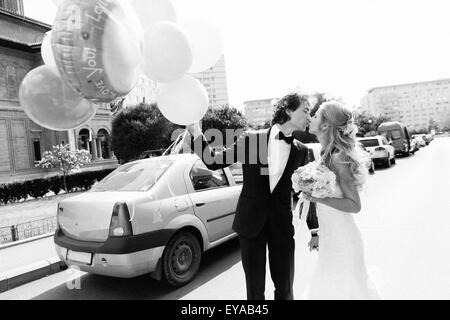 Just married junge Paar küssen auf einer Straße. Schwarz / weiß Bild mit Korn Film als Effekt hinzugefügt. Stockfoto