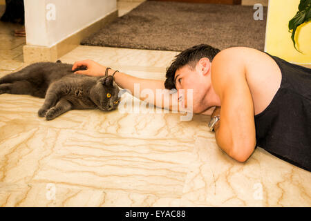 Der junge Mann am Boden liegend und weiche graue Katze, verbringen Zeit mit Haustier streicheln hautnah Stockfoto