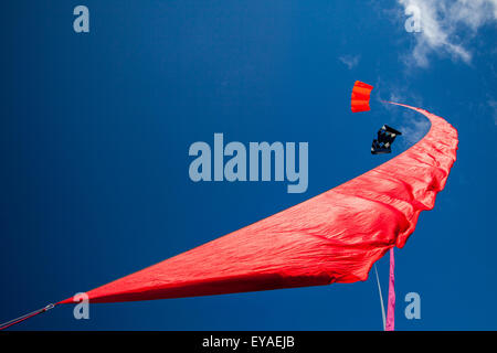 Bunte, geschwungene fliegende Dampfer Drachen segeln in den Himmel in Lytham, Lancashire, UK Kites Trailing Material beim St Annes Kite Festival am 25th. Und 26th. Juli 2015. Der Himmel über der Strandpromenade ist bunt, denn am Strand neben dem Pier werden riesige Drachen in die Luft gejagt. Das Festival zeigte Single Line, Dual Line, Quad Line und Power Kites, Windsock, weich, aufblasbare, Banner, Und Stunt-Drachen in allen Formen und Größen mit einer Vielzahl von Kitesurf-Stoffen Stockfoto