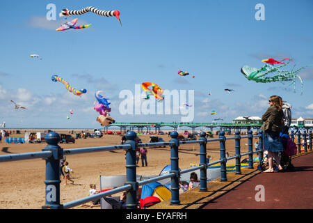 People Watching the St Annes Kite Festival, Lytham-St-Annes, Lancashire, Großbritannien, am 25th. Juli 2015. Der Himmel über der Strandpromenade ist farbenstrahlend, da am Strand neben dem Pier riesige Drachen zu sehen sind. Das Festival zeigte einzeilige, zweizeilige, vierzeilige und Power-Drachen, Windsocken, weiche, aufblasbare, Banner, Und Stunt-Drachen in allen Formen und Größen mit einer Vielzahl von Kitesurf-Stoffen Stockfoto