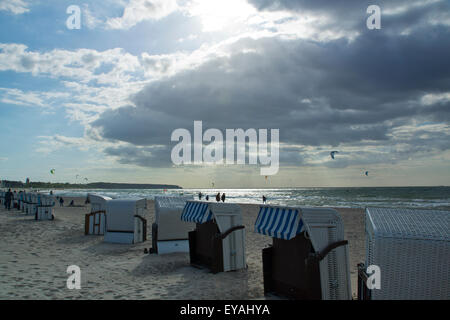 Die Sonne bricht durch dramatische Wolken über Warnemünde Strand, Ostsee, Mecklenburg-Vorpommern, Deutschland. Kitesurfer in Aktion Stockfoto