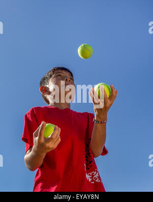 Junge jongliert Tennisbälle. Stockfoto