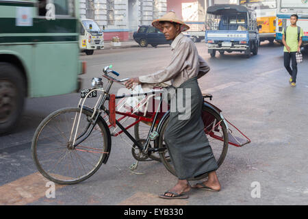 Yangon, Myanmar-Mai 8. 2014: AA Mann schiebt sein Fahrrad entlang einer Straße.  Fahrräder sind immer noch ein alltäglicher Anblick in der Stadt. Stockfoto