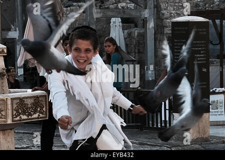 Jerusalem, Israel. 26. Juli 2015. Ein kleiner Junge jagt Tauben an der Klagemauer als Tausende von Gläubigen Juden beten auf Tisha B'Av, 9. des hebräischen Monats von Av, zum Gedenken an die Zerstörung des ersten Tempels (babylonischen König Nebukadnezar II, 587 v. Chr.) und des zweiten Tempels (70 CE, römische Legionen unter Titus). Bildnachweis: Nir Alon/Alamy Live-Nachrichten Stockfoto