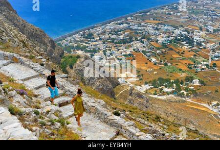 Touristen die Website des antiken Thira, Santorin, Griechenland von Messa Vouno Berg hinunter. Mit Perissa im Hintergrund Stockfoto