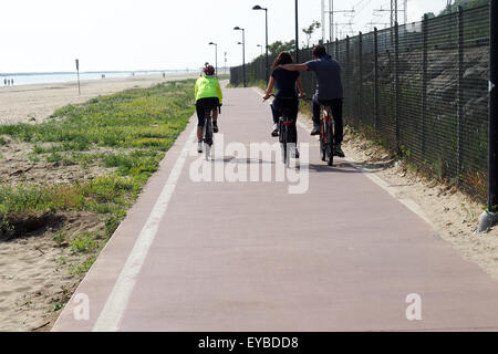 Touring, Radfahrer und ein paar umarmen einander, während sie auf einem Radweg am Strand fahren. Stockfoto