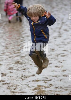 Malmesbury, Wiltshire, UK. 26. Juli 2015. Ein kleiner Junge springt in den Schlamm beim WOMAD-Festival in Charlton Park, Gloucestershire statt. 26. Juli 2015. Bildnachweis: Adam Gasson/Alamy Live-Nachrichten Stockfoto