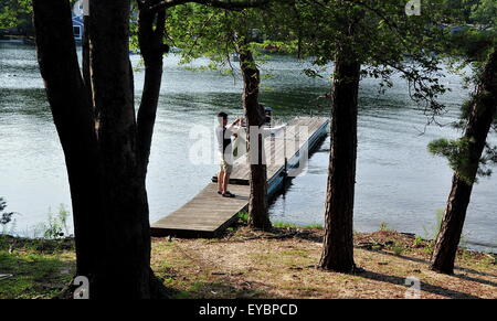 Centerville, MA: Junger Mann auf einem hölzernen Pier nimmt ein Foto der See Wequaquet, der größte Süßwasser-See in Cape Cod Stockfoto
