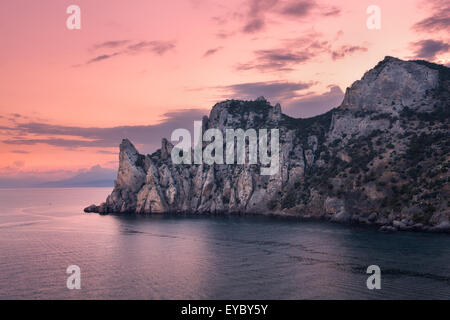 Schönen Sommer Sonnenuntergang am Meer mit Bergen, Steinen, Bäumen und bewölktem Himmel auf der Krim. Dämmerung, Dämmerung. Stockfoto