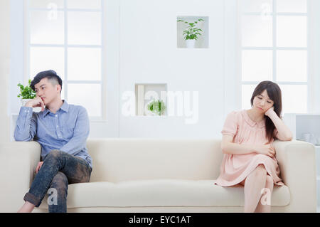Junger Mann und schwangere Frau sitzt auf dem Sofa mit schlechter Laune, Stockfoto