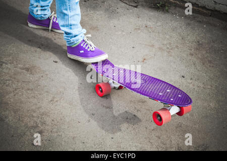 Junge Skater Füße Detektive und Jeans auf seinem Skate stehen. Closeup Fragment der Skateboard und Füße, Foto mit Retro-t Stockfoto