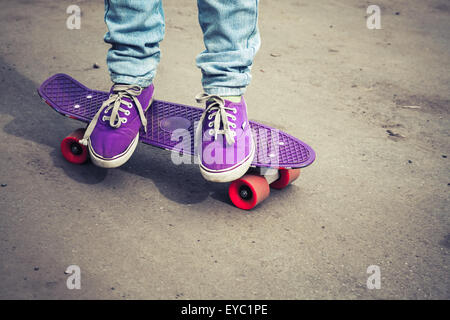 Junge Skater Füße Detektive und Jeans auf seinem Skate stehen. Close-up Fragment der Skateboard und Füße, Foto mit retro Stockfoto