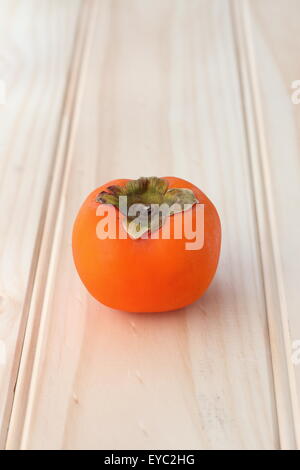 Ein frisches orange Farbe Kaki auf einem Holzbrett Stockfoto