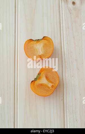 Ein frische Orange Farbe Kaki halbieren auf einem Holzbrett Stockfoto