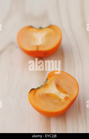 Ein frische Orange Farbe Kaki halbieren auf einem Holzbrett Stockfoto