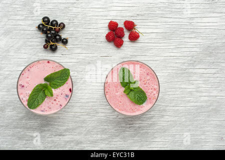 Frische Milch, Johannisbeere, Himbeere und rote Johannisbeere Getränke auf Wodeen Tisch, verschiedene Protein-Cocktails mit frischen Früchten Stockfoto