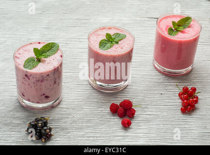 Frische Milch, Johannisbeere, Himbeere und rote Johannisbeere Getränke auf Wodeen Tisch, verschiedene Protein-Cocktails mit frischen Früchten Stockfoto