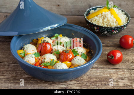 Marokkanische Tajine mit Huhn Kefta (Frikadellen), rote und gelbe Tomaten, Paprika und Bulgur auf einem Holztisch, selektiven Fokus Stockfoto