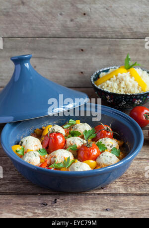 Marokkanische Tajine mit Huhn Kefta (Frikadellen), rote und gelbe Tomaten, Paprika und Bulgur auf einem Holztisch, selektiven Fokus Stockfoto
