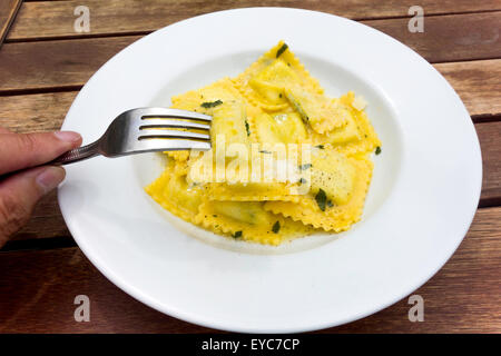 Pub Mittagessen Ravioli Pasta gefüllt mit Spinat und Ricotta-Käse mit Butter Pfeffer und Parmesan Hand gehalten Gabel als Flocken Stockfoto