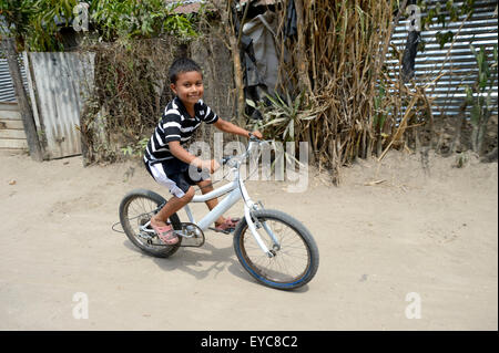 Junge sein Fahrrad aus einer Friedensinitiative von der Polizei und der katholischen Kirche in den Slums von Colonia Monsenor Romero Stockfoto