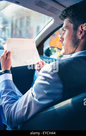 Geschäftsmann lesen Zeitung im Auto Stockfoto