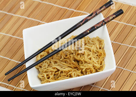 Chinesische Nudeln in Schale und Stäbchen auf Bambusmatte Stockfoto