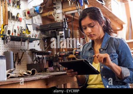 Weibliche Mechaniker mit digital-Tablette in Werkstatt Stockfoto