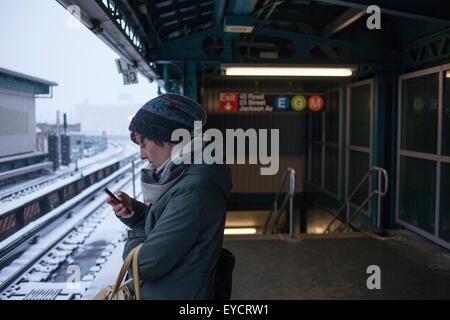 Mitte erwachsenen Frau stehen am Bahnhof mit Handy Stockfoto