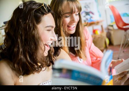 Zwei junge Freundinnen stöbern und lachen über Bücher Stockfoto