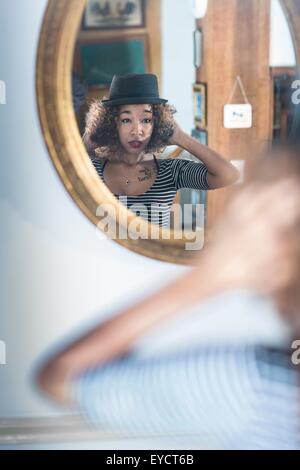 Junge Frau in Wandspiegel anprobieren fedora Stockfoto
