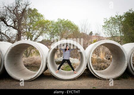 Porträt der jungen Frau in Betonrohr im ländlichen Landschaft Stockfoto