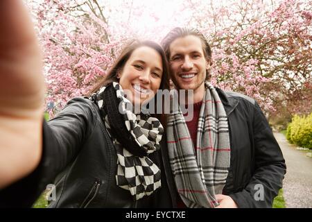 Junges Paar posieren für Selfie mit Blüte im park Stockfoto