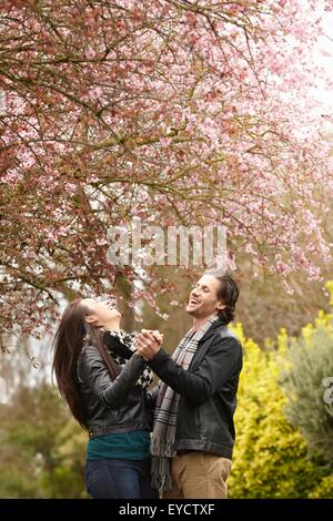 Junge Paare tanzen unter blühen im park Stockfoto