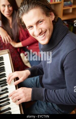 Porträt des jungen Mannes mit dem Klavierspiel für Freundin Stockfoto