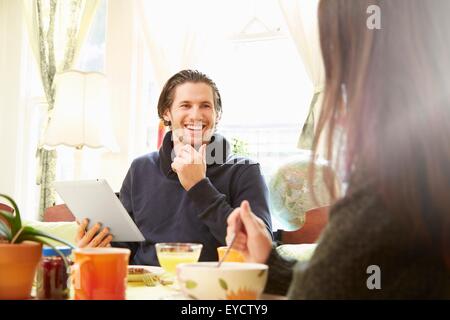 Über Schulter Blick des jungen Mannes mit digital-Tablette am Frühstückstisch Stockfoto