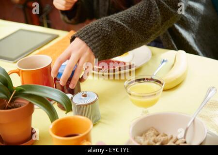 Schuss von jungen Womans Hände halten Marmeladenglas am Frühstückstisch beschnitten Stockfoto
