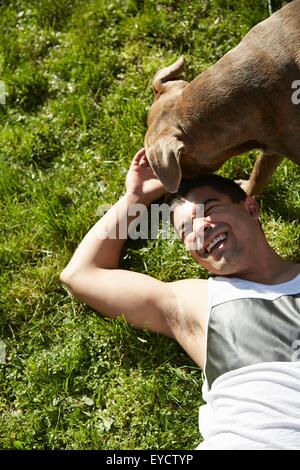 Draufsicht der junge Mann mit Hund auf dem Rasen spielen Stockfoto