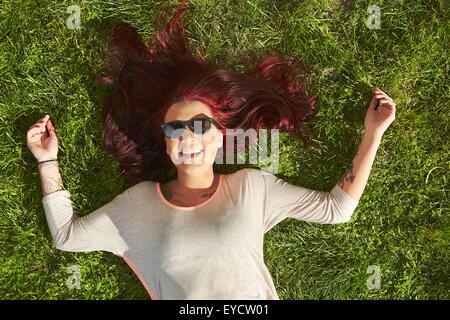 Draufsicht der jungen Frau mit roten Haaren auf dem Rasen liegend Stockfoto