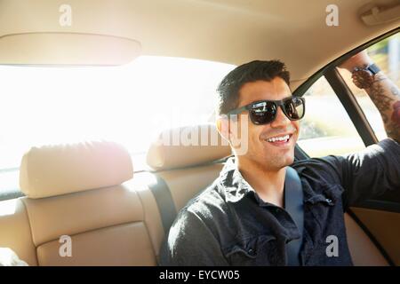 Lächelnder junge Mann im Rücksitz des Wagens Stockfoto