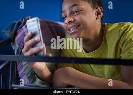 Nahaufnahme von Teenager im Etagenbett Smartphone Text lesen liegend Stockfoto